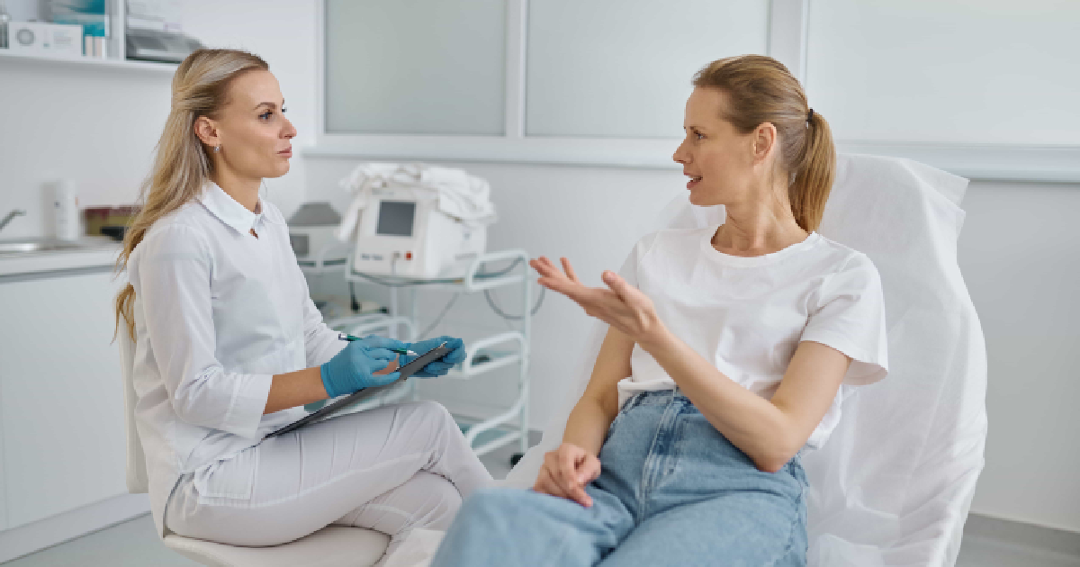 A woman in a white uniform listens to a client during a Medspa skin consultation in Bothell, WA.